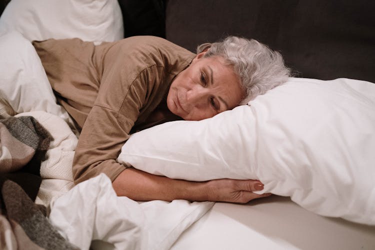 Elderly Woman Lying On White Pillow