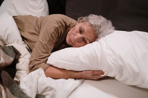 Free Senior woman lying on a pillow in bed, appearing thoughtful and calm. Stock Photo