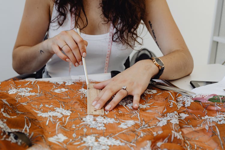 A Seamstress Measuring A Fabric