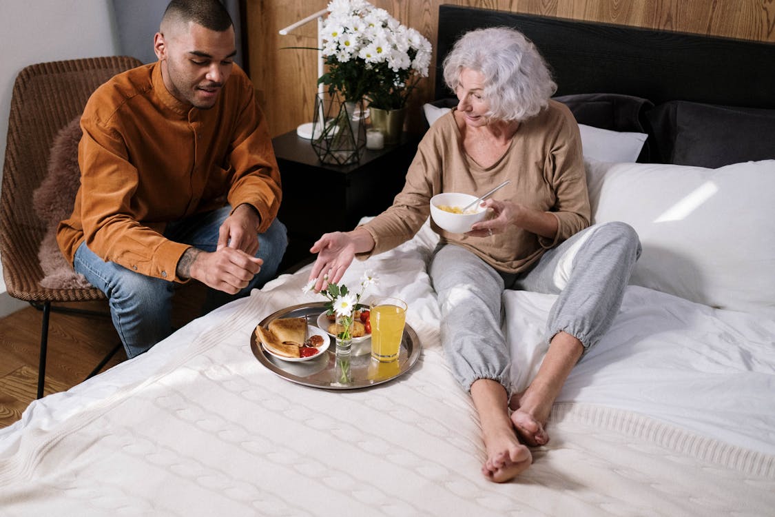 Free An Elderly Woman Sitting on the Bed while Talking to Her Grandson Stock Photo