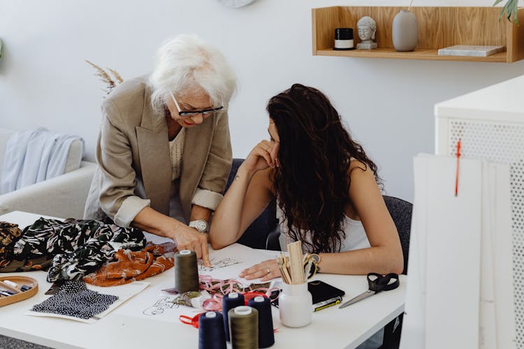 An Elderly Woman Teaching Her Granddaughter While Pointing Finger On The Table