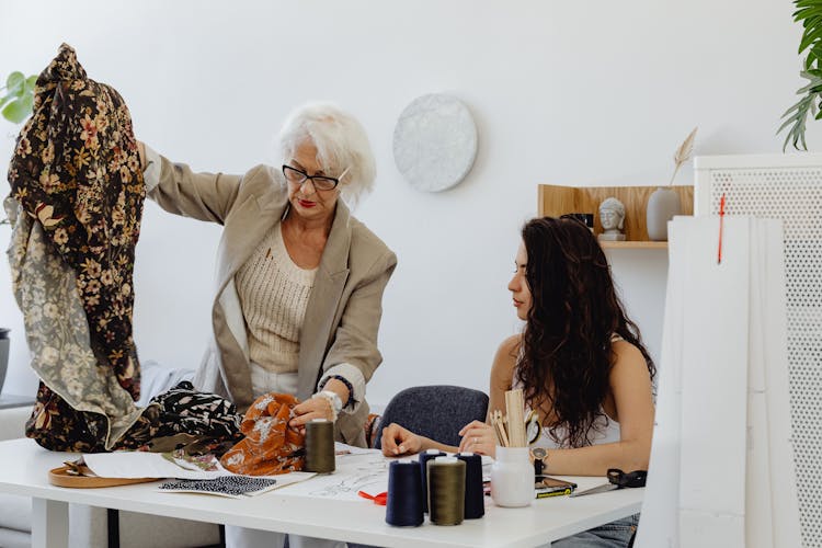 An Elderly Woman Holding A Printed Cloth While Talking To Her Granddaughter