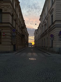 Charming sunset view through a narrow street flanked by classic European architecture.
