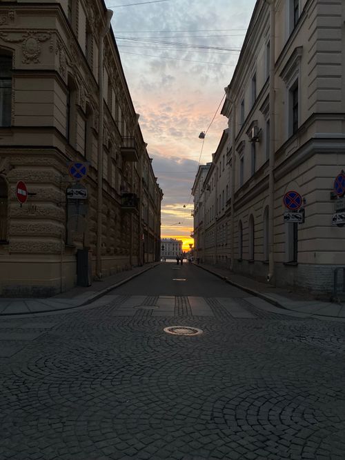 Free Charming sunset view through a narrow street flanked by classic European architecture. Stock Photo