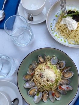 Overhead view of gourmet seafood pasta with clams and creamy spaghetti on a marble table.
