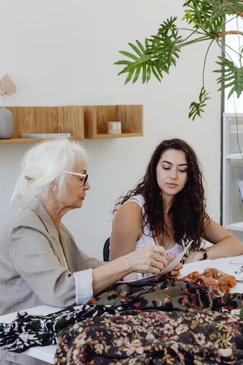 Free Woman in White Tank Top Sitting Beside the Elderly Woman  Stock Photo