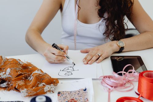 Free Fashion designer sketching ideas with fabric samples and tools on her table. Stock Photo