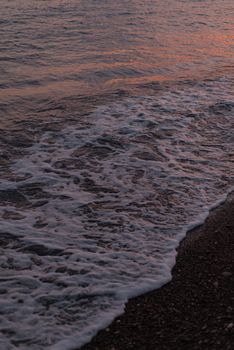 Gentle waves crashing on a beach at sunset, capturing nature's tranquility.