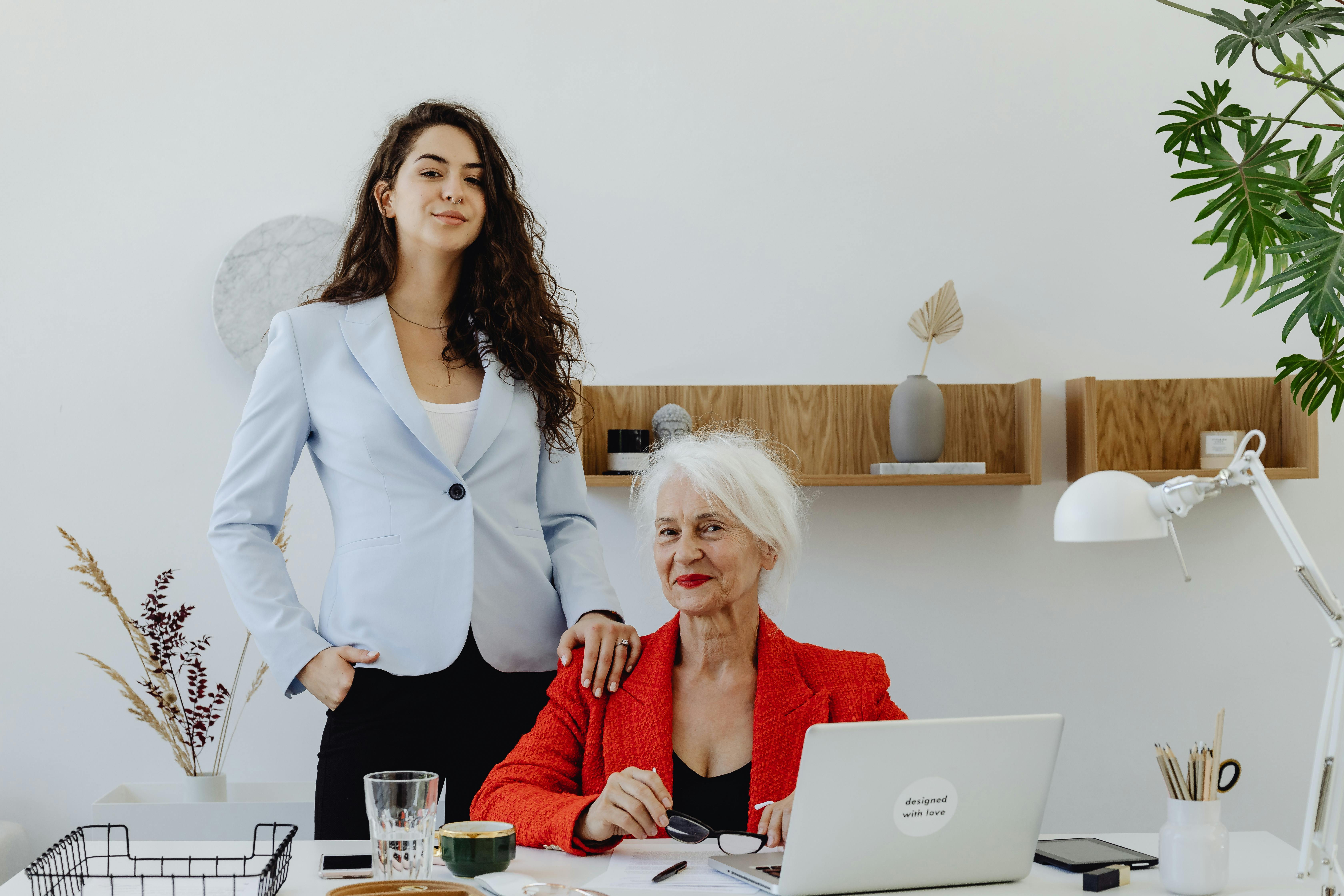 Two professional women in a stylish office environment, showcasing teamwork and confidence.
