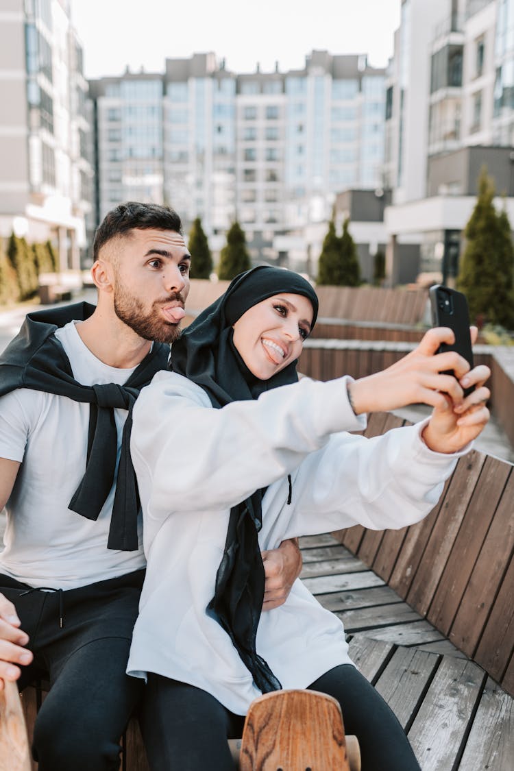 A Woman In White Sweater Taking Selfie With Her Boyfriend