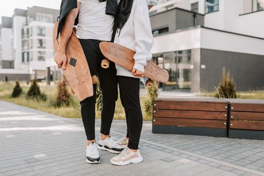Young couple holding skateboards in a modern urban area, enjoying outdoor leisure.