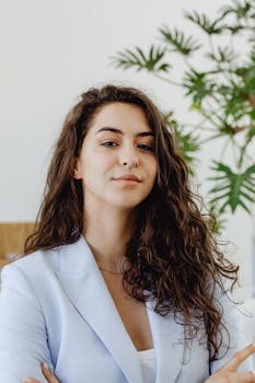 Portrait of a confident businesswoman with wavy hair wearing a blazer indoors.