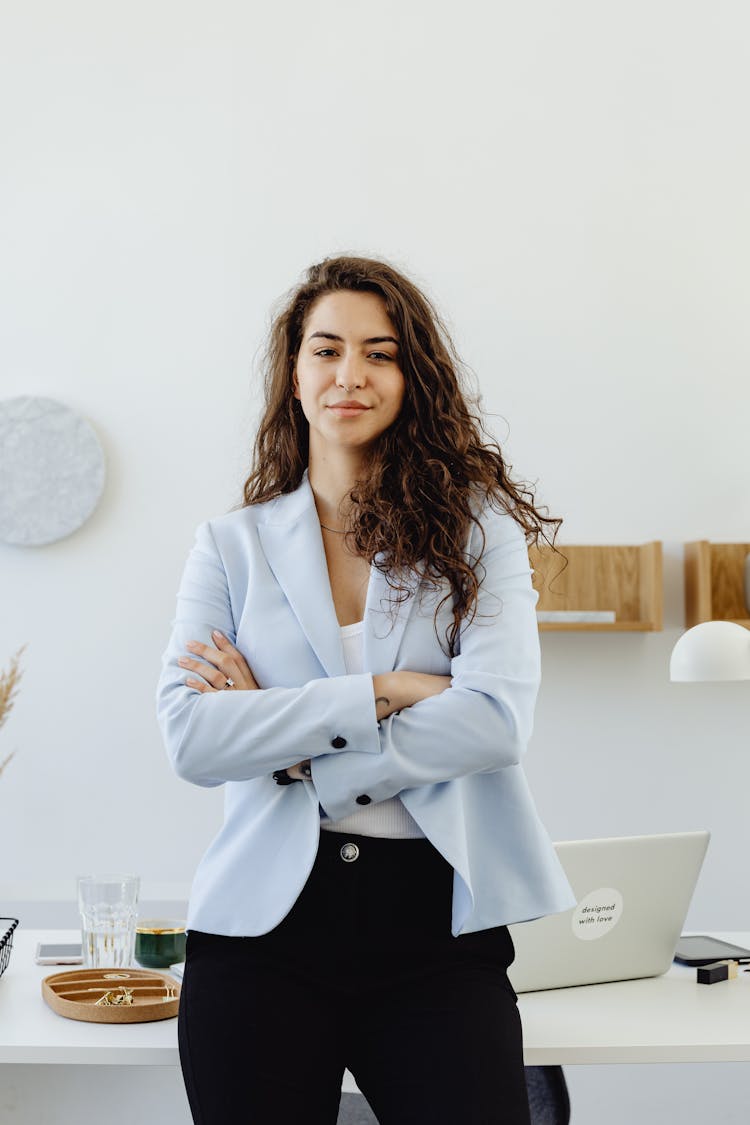 A Woman In White Blazer Smiling With Her Arms Crossed