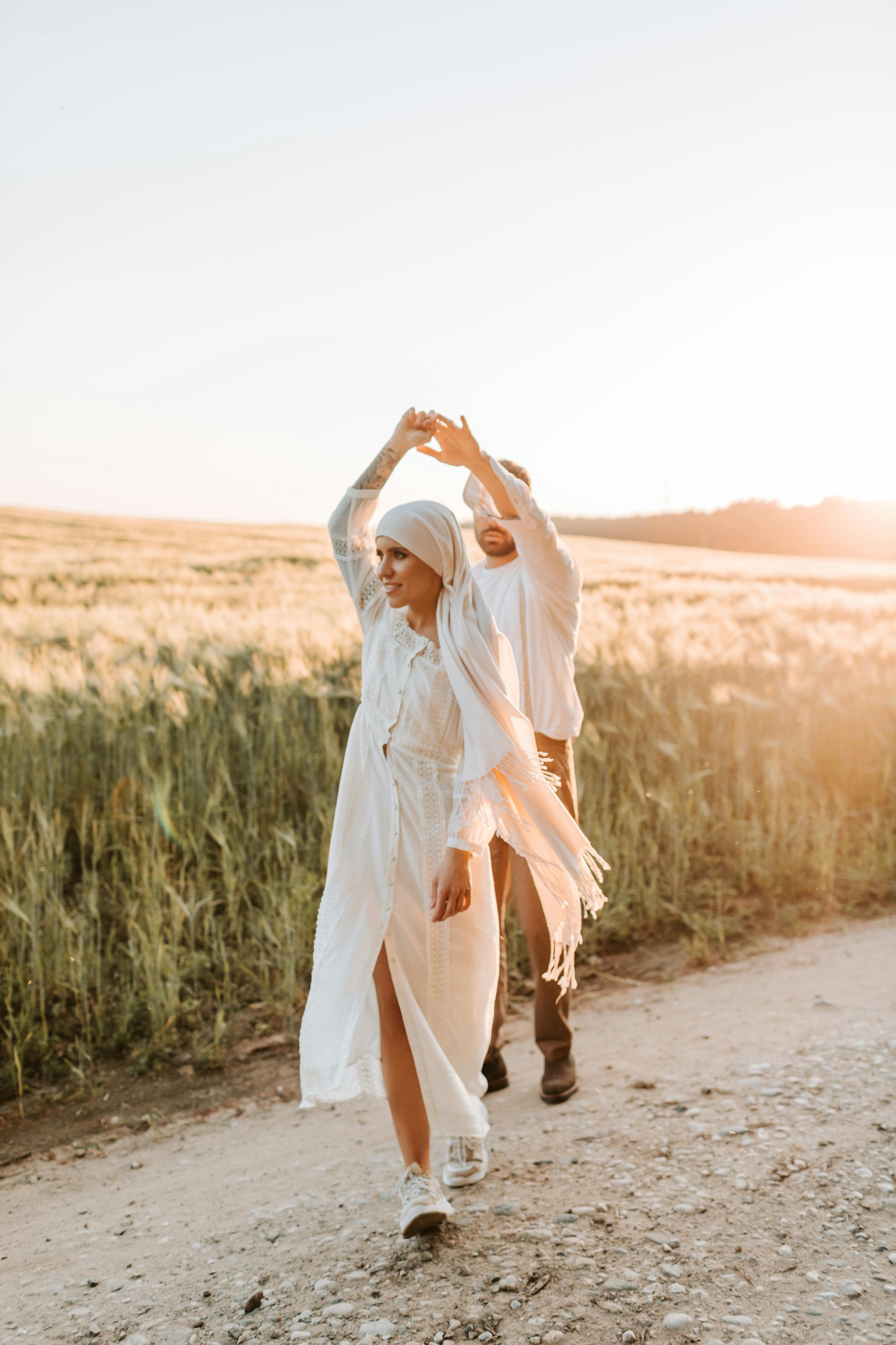 A couple in love dances joyfully along a rural path during sunset, capturing romance and freedom.