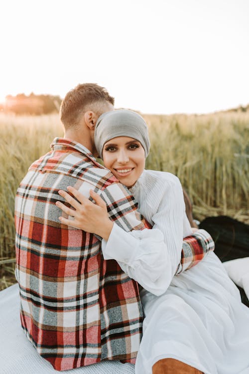 Free A Woman in White Dress Embracing a Man in Plaid Long Sleeves Stock Photo