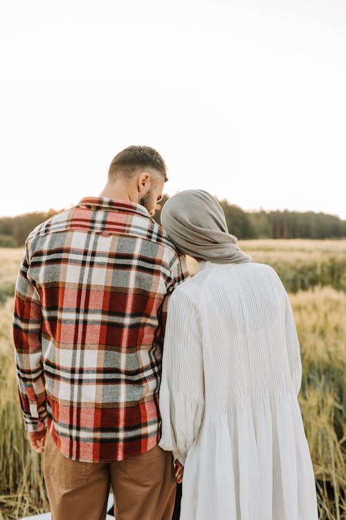 A Couple Standing on the Grass Field