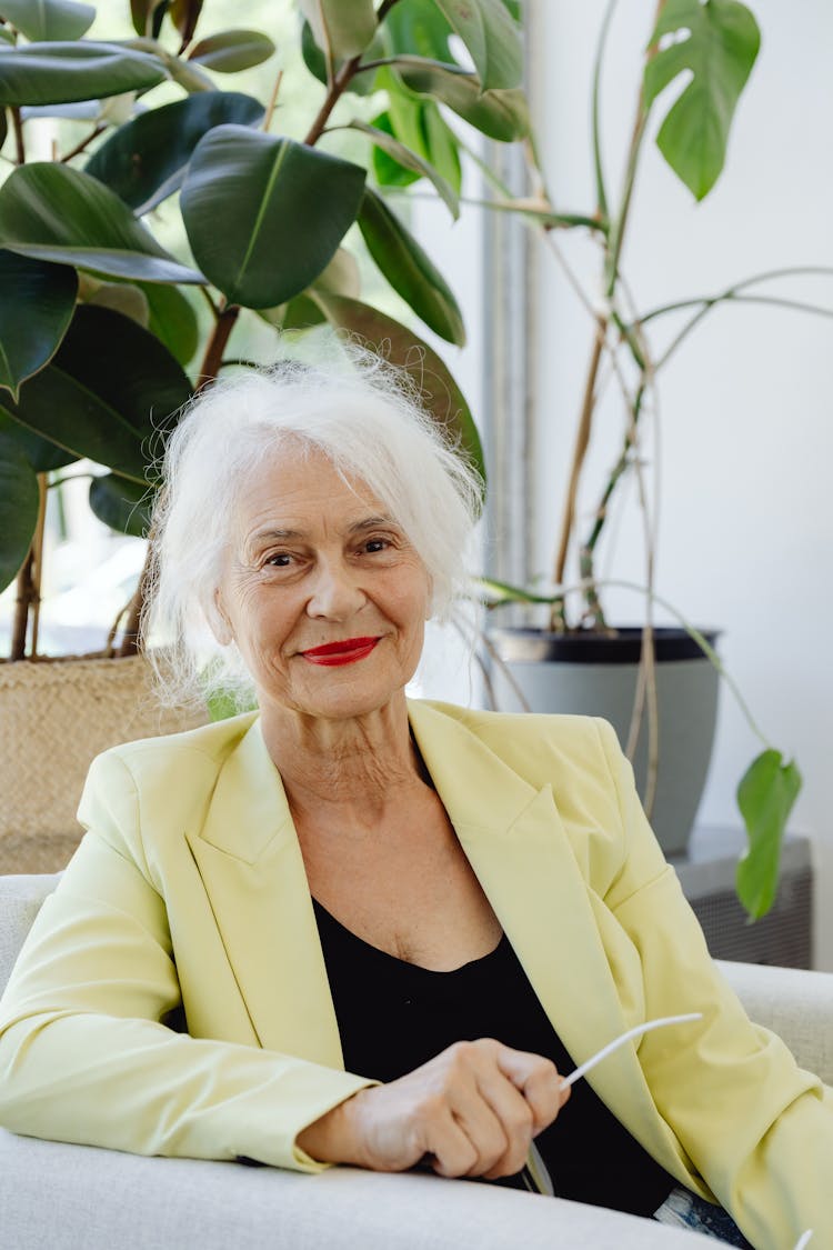 A Smiling Lady Wearing A Black Blouse And A Yellow Blazer