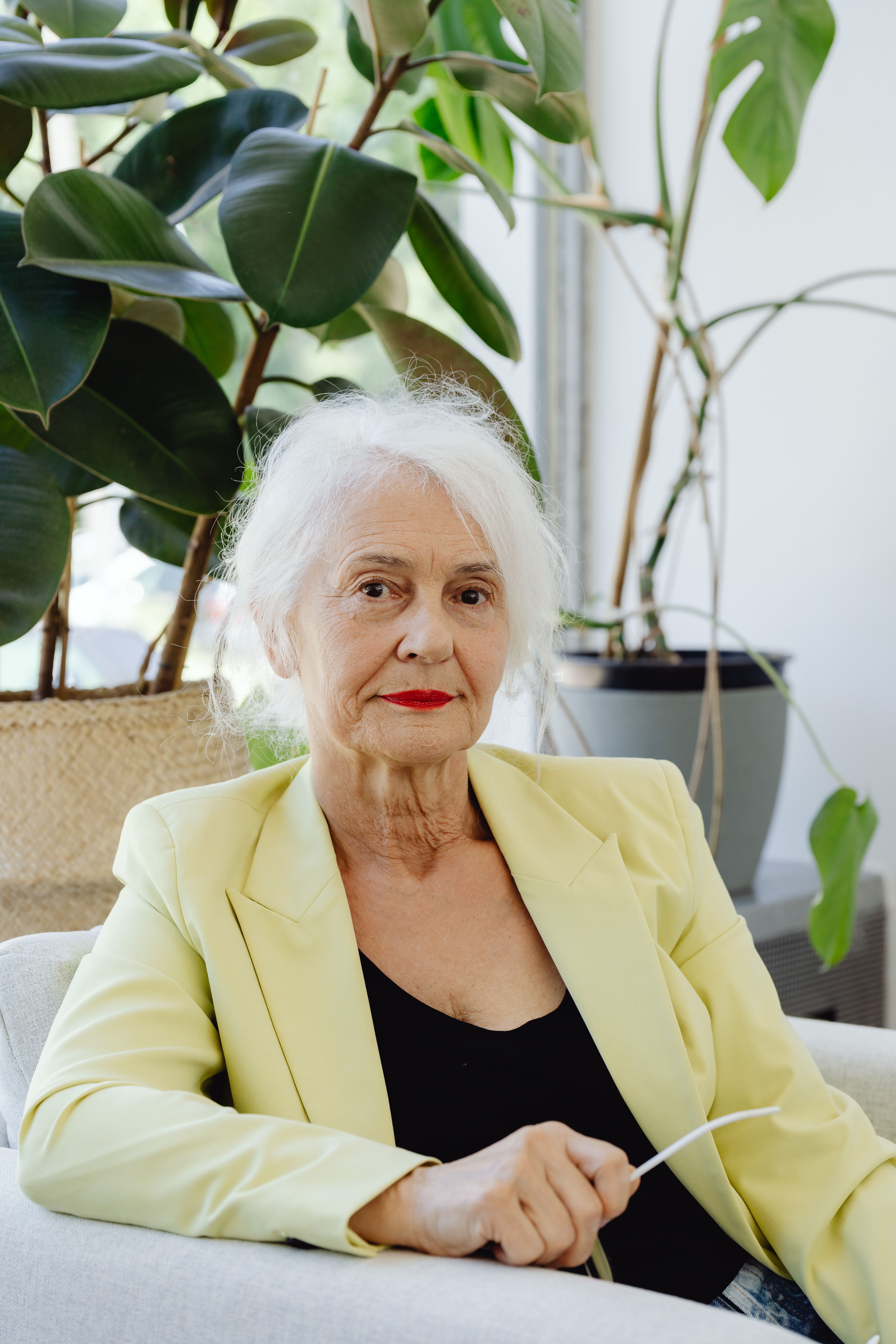 Portrait of an elderly woman in yellow blazer with a serene expression indoors.