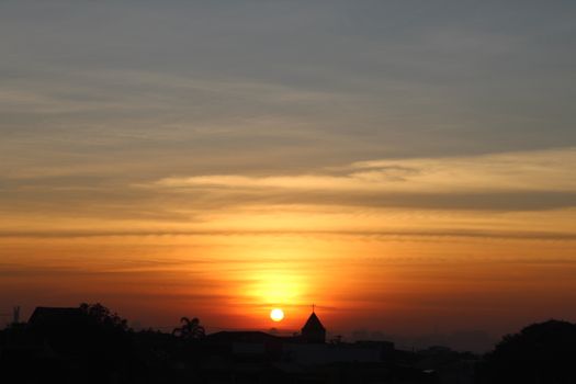 Beautiful sunrise with city skyline silhouette, dramatic orange hues and tranquil atmosphere.