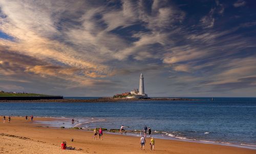 Free Picturesque beach scene featuring a lighthouse under a dramatic sky. Stock Photo