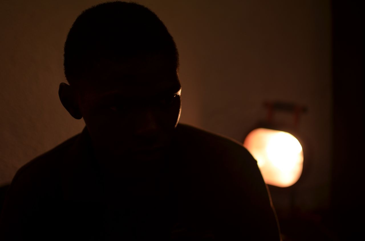 a mysterious silhouette of an adult in warm dim indoor lighting in bam