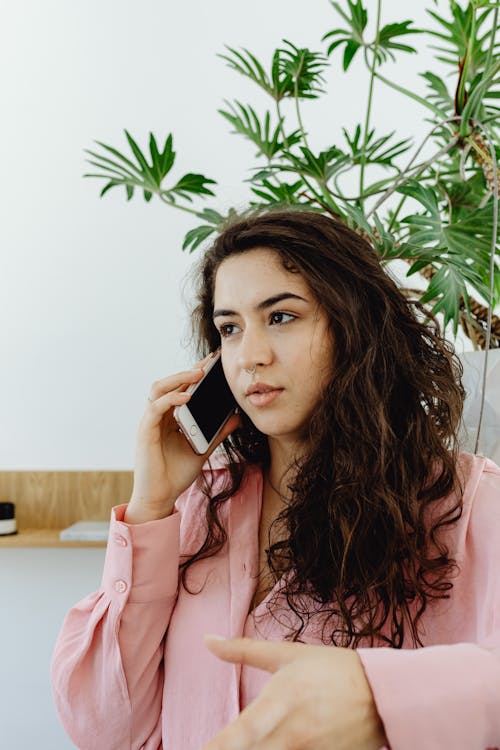 A Curly-Haired Woman in Pink Long Sleeves Having a Phone Call