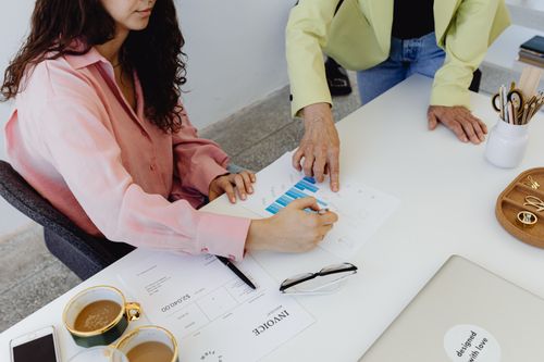 Free Two colleagues work together on financial graphs, promoting teamwork in a modern office setting. Stock Photo