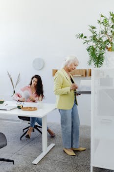 Two women working in a modern and stylish office space with plants and minimalist decor.