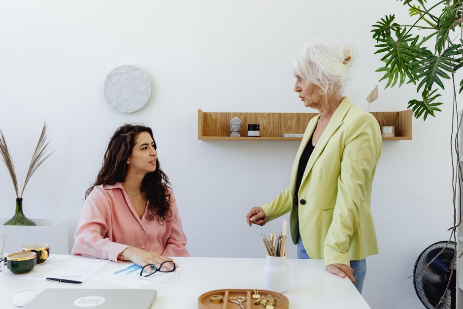 Dos mujeres involucradas en una discusión profesional en un espacio de oficina brillante.
