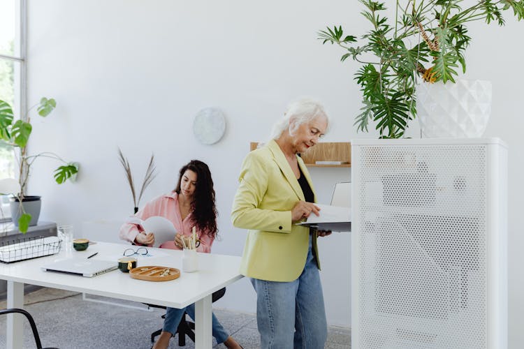 Gray Haired Woman In Green Blazer Looking At The Documents 