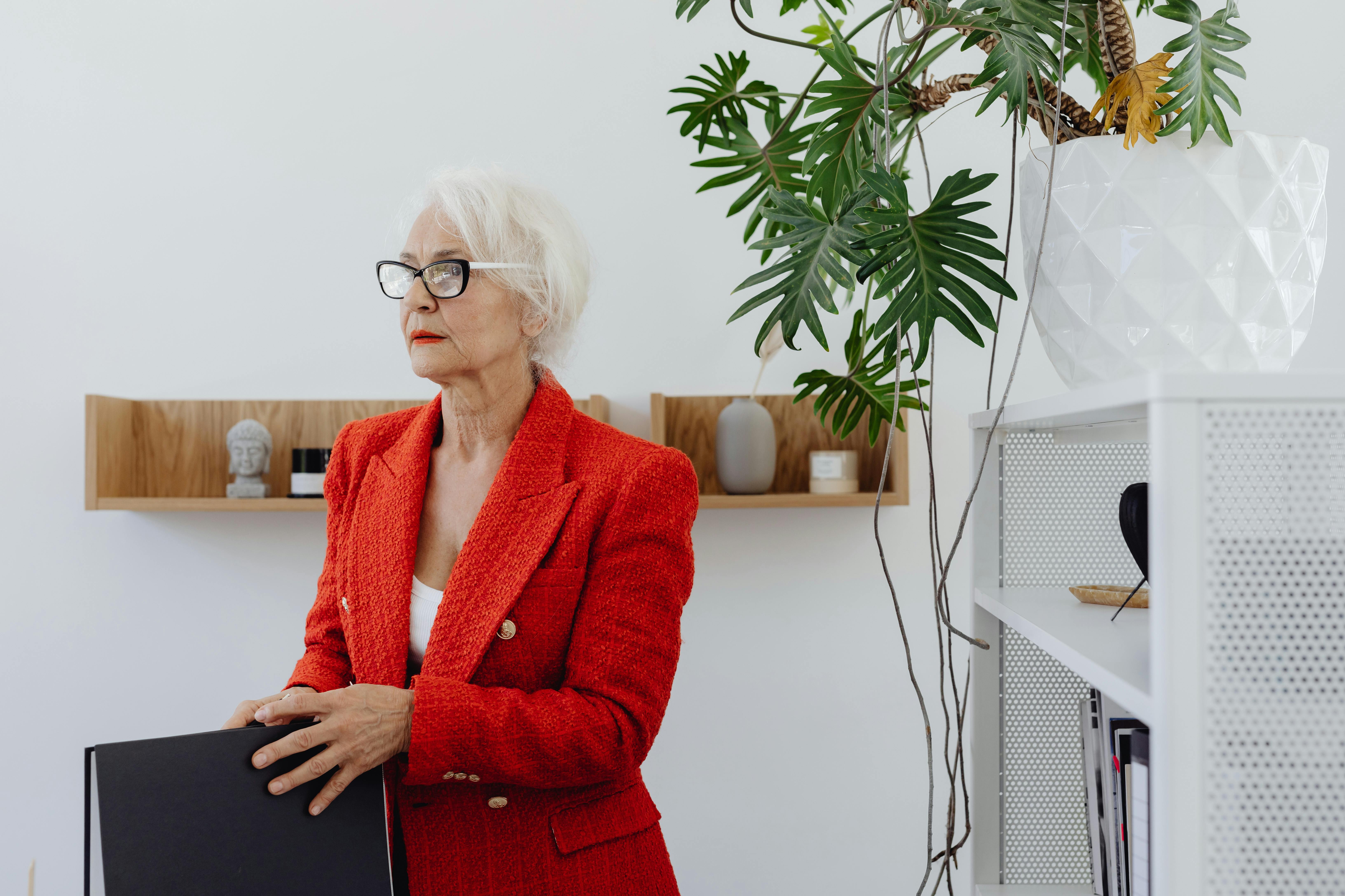 Sophisticated senior businesswoman holding a binder in a modern office interior.