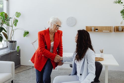 Free Two businesswomen shaking hands in a bright and modern office setting. Stock Photo