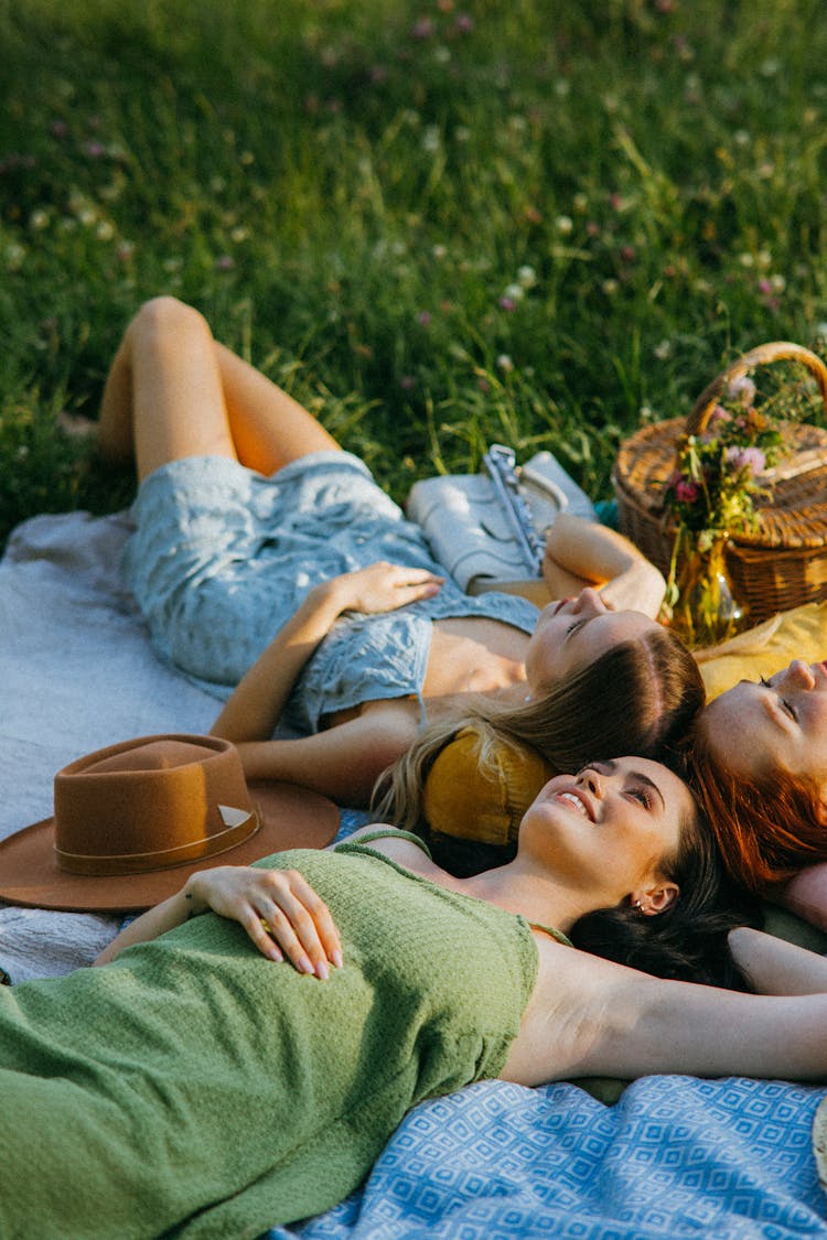 Women Lying Down Over Picnic Blankets Laid On Grass