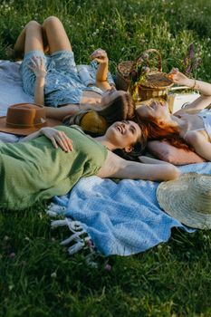 A cheerful group of adult women relaxing on a picnic blanket in a lush green park.