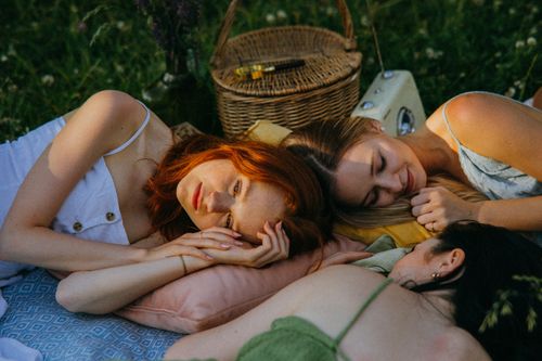 Free Three women lying in a meadow having a relaxing picnic on a summer day. Stock Photo