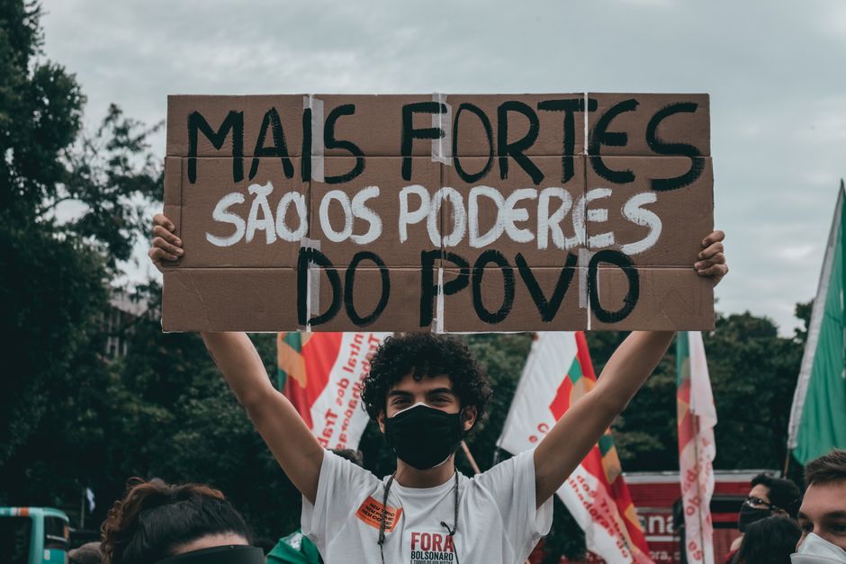 Protester in Rio holds sign saying 'Mais fortes são os poderes do povo.'