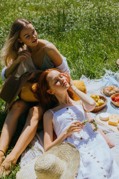Free Two women enjoying a sunny picnic outdoors with fresh food and a relaxing atmosphere. Stock Photo