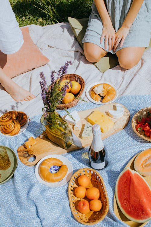 Free A Person Sitting on a Picnic Blanket with Different Kinds of Food Stock Photo