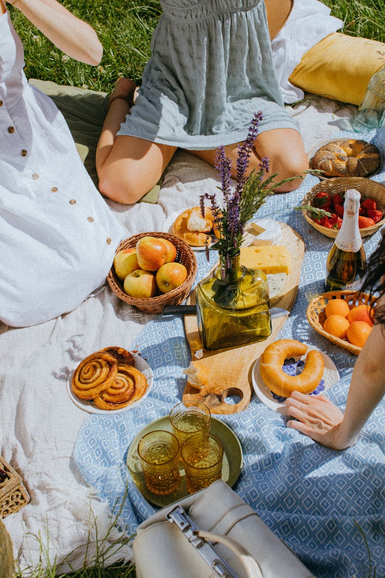 A Group Of People Having Picnic With Fruits And Bread