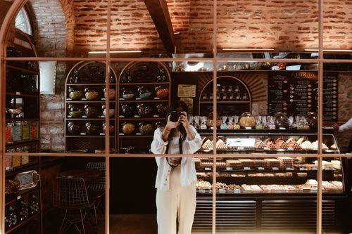 Free Reflection of a photographer in a cozy cafe with rustic interior and vibrant display. Stock Photo