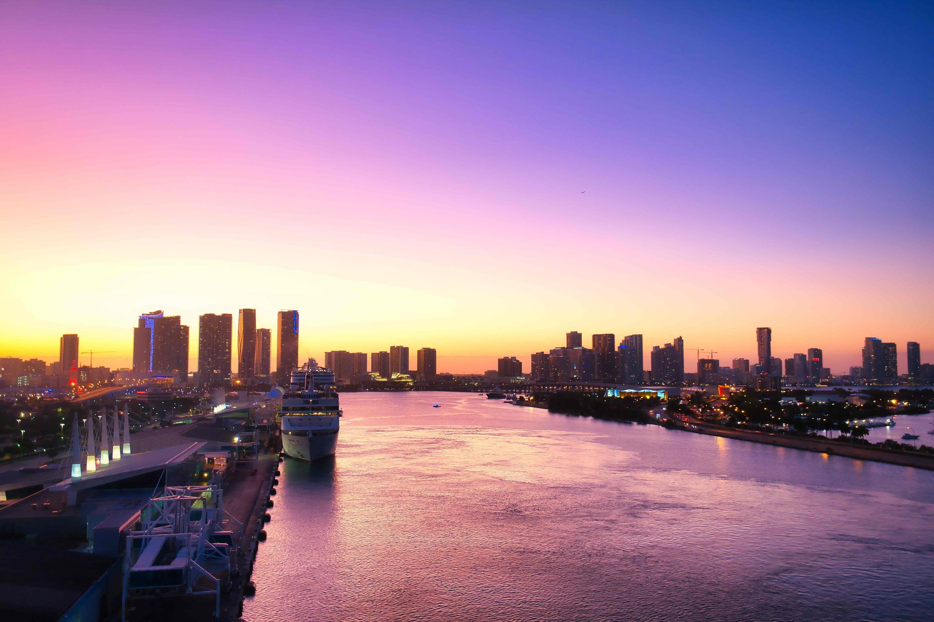 Miami skyline at sunset with vibrant pink and purple sky reflecting on Biscayne Bay