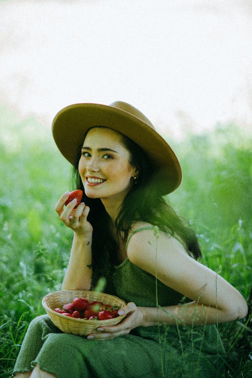 Woman Wearing Hat Holding a Strawberry
