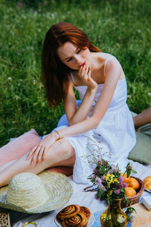 Woman in White Dress Sitting on a Picnic Blanket