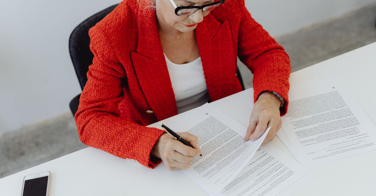 person reading contract on phone at desk