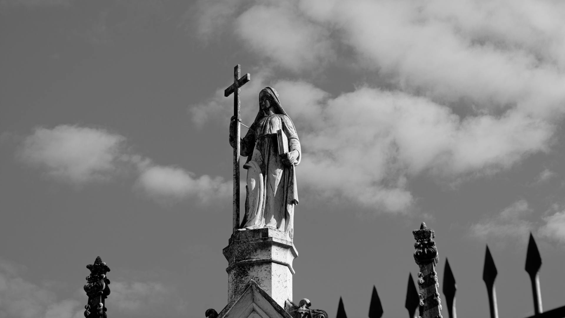 Black and White Photo of Statue of Saint on Top of Church