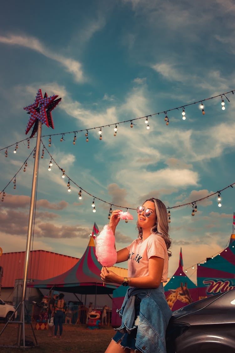 Woman Eating Pink Cotton Candy At A Fun Fair 