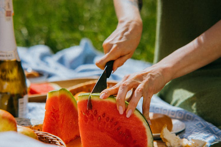 Person Slicing Watermelon Into Small Pieces