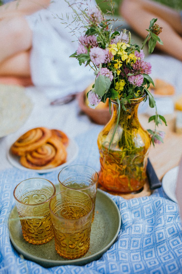 Drinking Glasses On A Round Tray Beside A Vase With Flowers