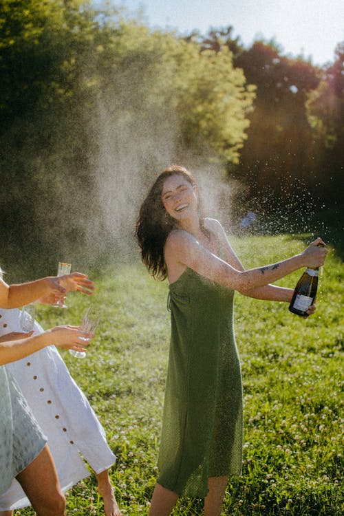 A Woman in Green Dress Holding a Bottle of Champagne