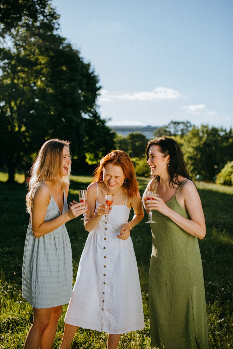 Women In Spaghetti Strap Dresses Holding Champagne Glasses